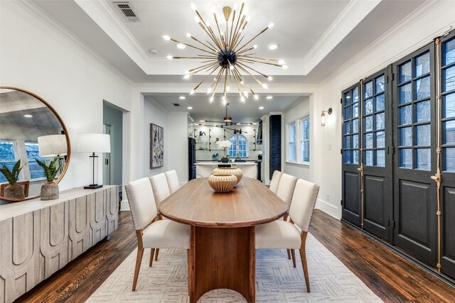 dining area featuring dark wood-style floors, a tray ceiling, crown molding, visible vents, and an inviting chandelier