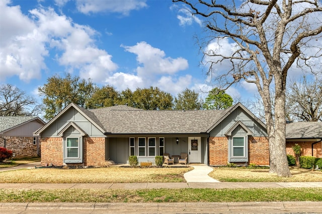 view of front of property featuring a shingled roof, board and batten siding, and brick siding