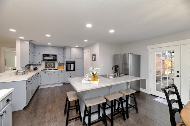 kitchen with dark wood-type flooring, light countertops, black appliances, a sink, and recessed lighting