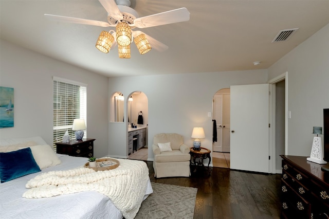 bedroom with arched walkways, visible vents, and wood finished floors