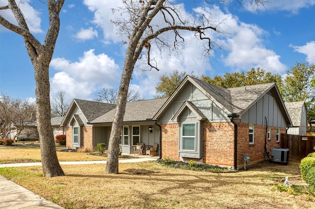 view of front of home featuring roof with shingles, a front yard, board and batten siding, and brick siding