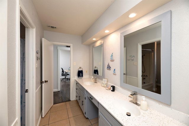 bathroom featuring double vanity, walk in shower, a sink, and tile patterned floors