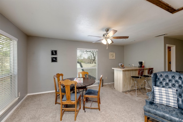 dining room with light carpet, a bar, visible vents, and baseboards