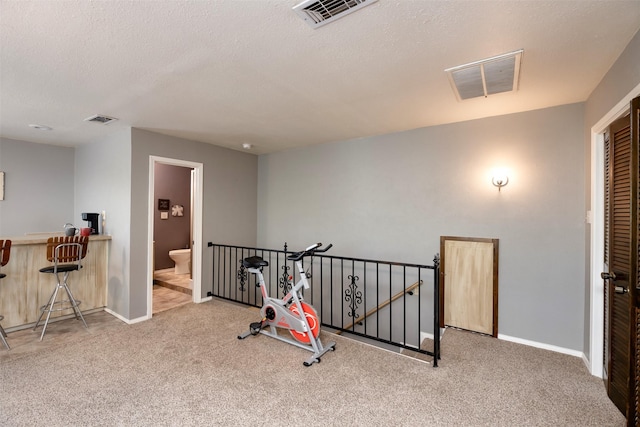 workout room with a textured ceiling, carpet, and visible vents