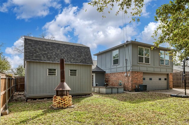 back of house with central AC unit, fence private yard, brick siding, a yard, and roof with shingles