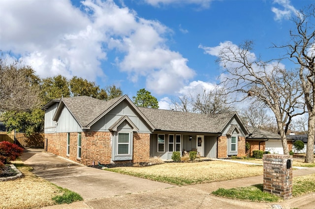 view of front of home featuring board and batten siding, brick siding, fence, and roof with shingles