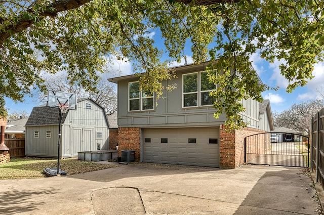 back of house with a garage, brick siding, fence, concrete driveway, and a gate