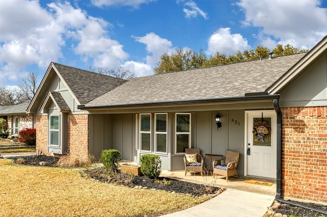 exterior space with brick siding, roof with shingles, and board and batten siding