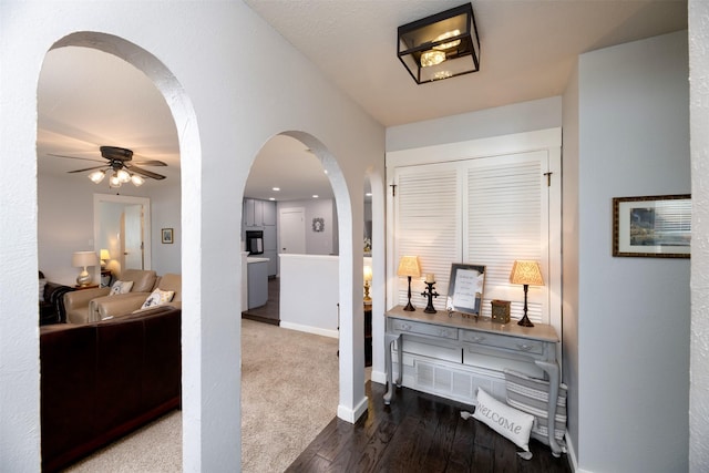 hallway featuring baseboards, arched walkways, and wood finished floors