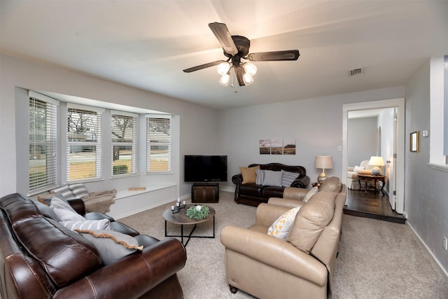 living room with baseboards, carpet floors, visible vents, and a ceiling fan