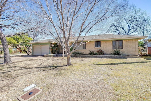 ranch-style house featuring driveway, brick siding, an attached garage, and a front yard