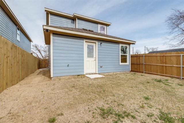 rear view of house featuring a lawn and a fenced backyard