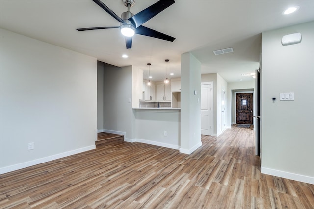 unfurnished living room featuring baseboards, visible vents, and light wood-style floors