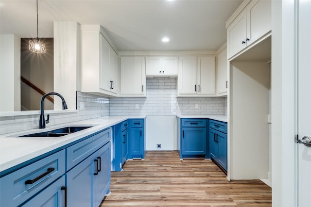 kitchen with blue cabinets, light wood-style floors, white cabinetry, and a sink