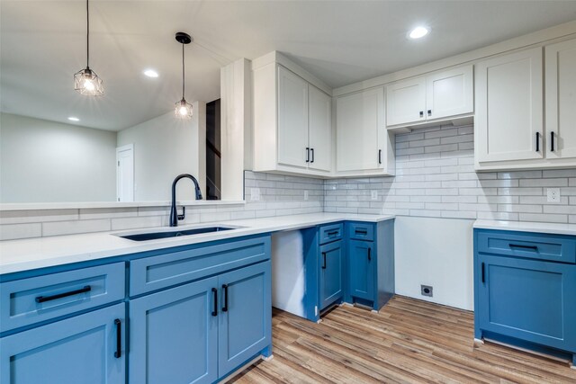 kitchen with blue cabinets, backsplash, a sink, and light wood-style flooring