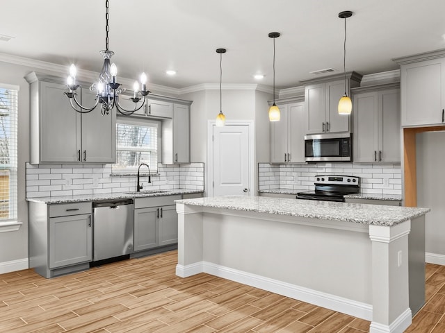 kitchen featuring crown molding, gray cabinetry, appliances with stainless steel finishes, wood tiled floor, and a sink