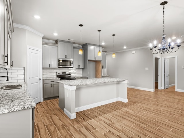 kitchen with wood finish floors, stainless steel appliances, backsplash, gray cabinetry, and a sink