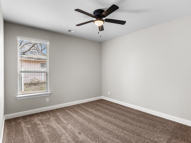 spare room featuring dark colored carpet, visible vents, and baseboards