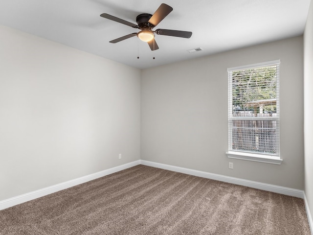 carpeted empty room with baseboards, visible vents, and a ceiling fan