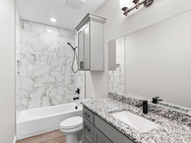 bathroom featuring wood finish floors, visible vents, toilet, vanity, and shower / tub combination