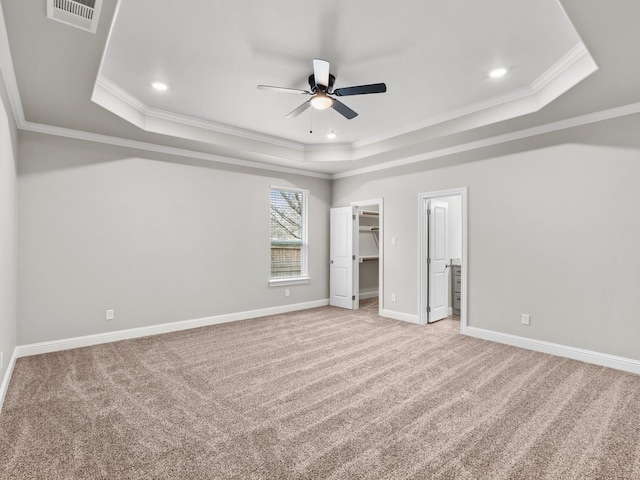 unfurnished bedroom featuring visible vents, baseboards, light colored carpet, ornamental molding, and a tray ceiling