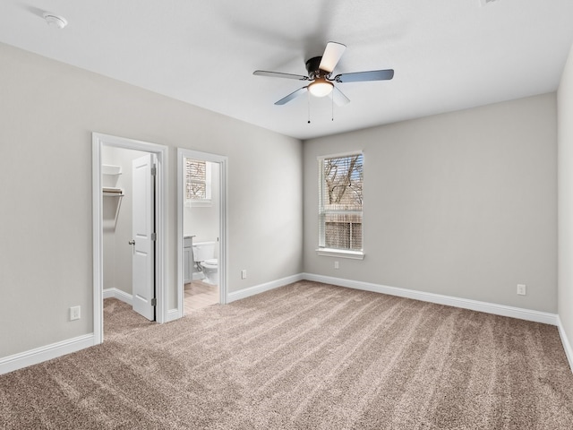 unfurnished bedroom featuring carpet, baseboards, a walk in closet, and connected bathroom