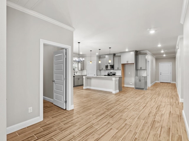 kitchen with wood finish floors, stainless steel appliances, decorative backsplash, gray cabinetry, and a sink