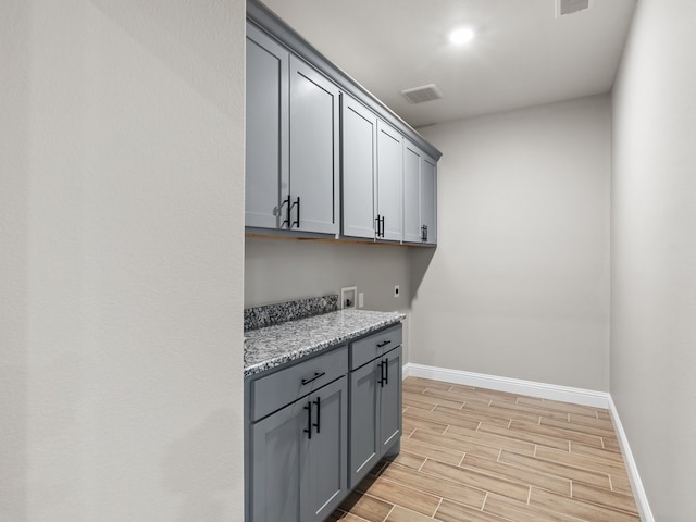 laundry area featuring cabinet space, baseboards, electric dryer hookup, and wood finish floors