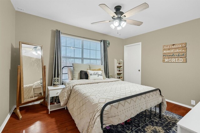 bedroom with ceiling fan, baseboards, and dark wood-type flooring