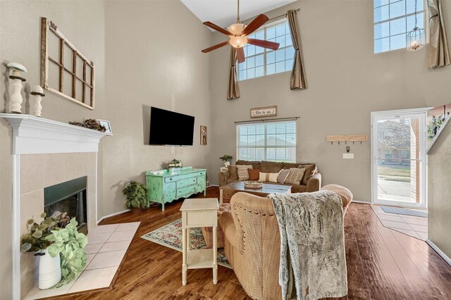 living room with a tiled fireplace, a wealth of natural light, and wood finished floors