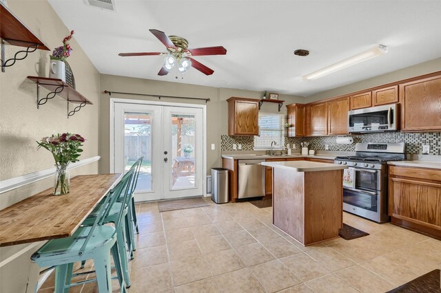 kitchen with tasteful backsplash, a kitchen island, stainless steel appliances, light countertops, and french doors