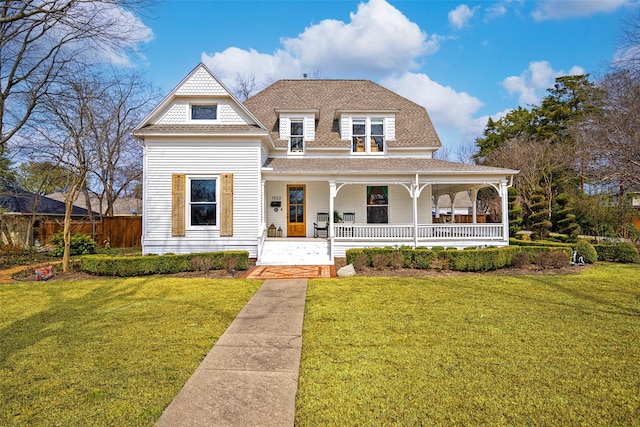 view of front of house featuring a shingled roof, a front yard, and covered porch