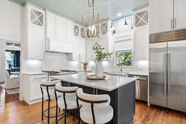 1502 W Virginia St, Mckinney, TX 75069 - kitchen with appliances with stainless steel finishes, a sink, a center island, white cabinetry, and light wood finished floors