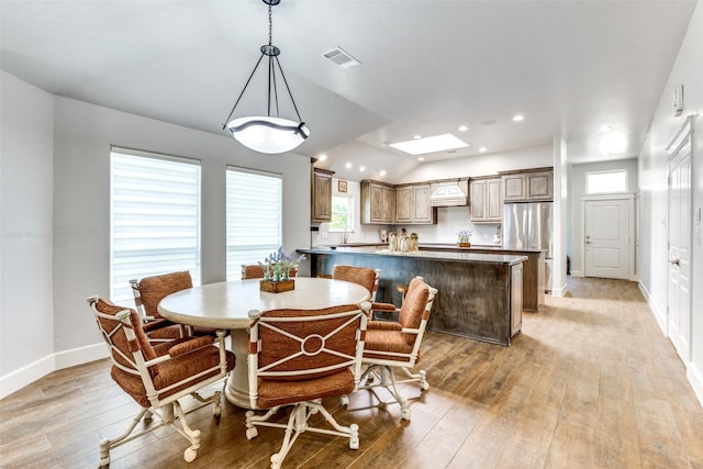 dining area featuring vaulted ceiling with skylight, visible vents, baseboards, light wood-type flooring, and recessed lighting