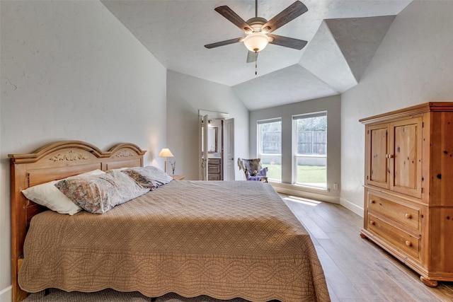 bedroom with light wood finished floors, a ceiling fan, connected bathroom, vaulted ceiling, and baseboards