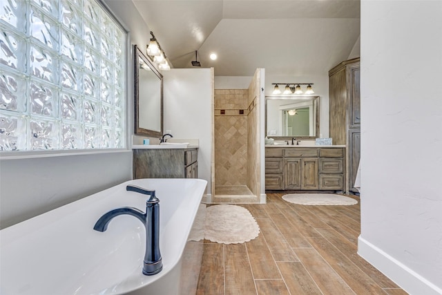 full bath with wood finish floors, a soaking tub, vaulted ceiling, a sink, and walk in shower