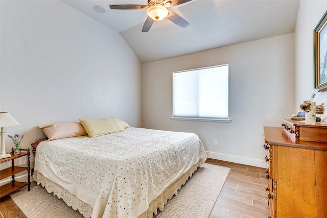 bedroom featuring lofted ceiling, light wood finished floors, a ceiling fan, and baseboards