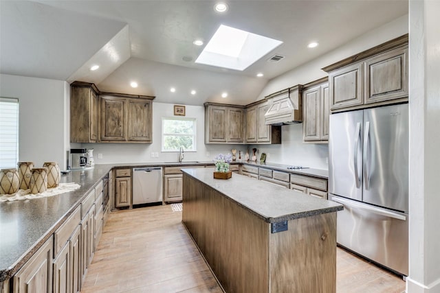 kitchen featuring visible vents, appliances with stainless steel finishes, a center island, custom exhaust hood, and light wood-type flooring