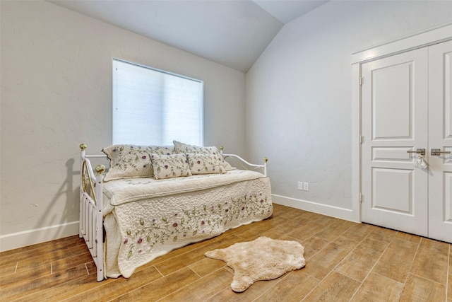 living area featuring vaulted ceiling, baseboards, and light wood-style floors