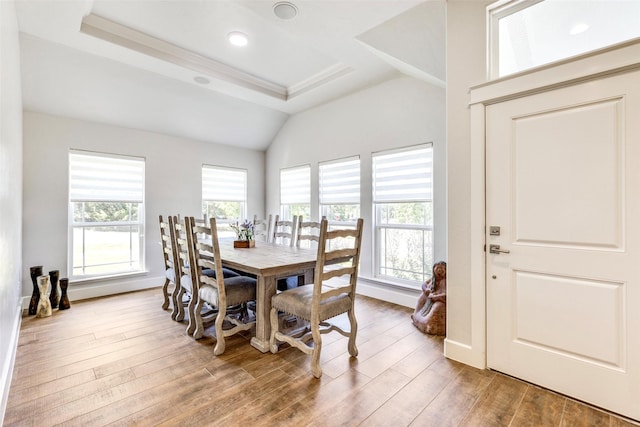 dining room featuring vaulted ceiling, a tray ceiling, wood finished floors, and baseboards