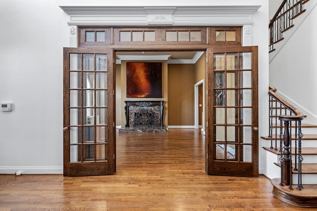 corridor featuring baseboards, stairway, wood finished floors, and crown molding