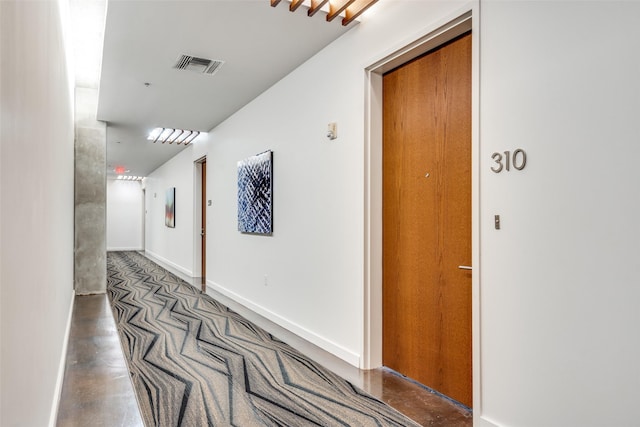 hall featuring baseboards, concrete floors, and visible vents