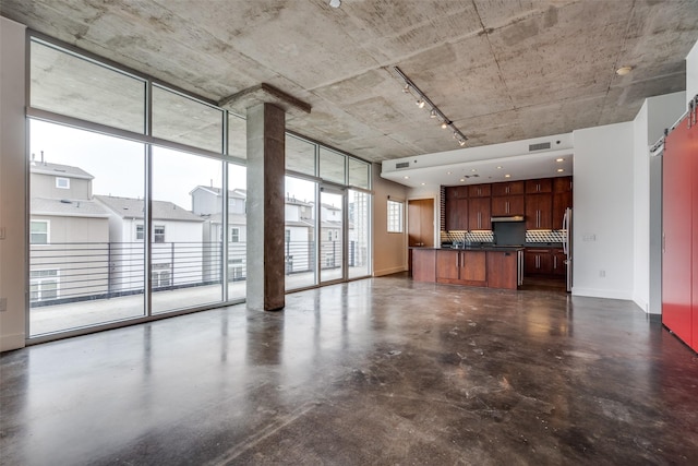 unfurnished living room featuring concrete floors, a sink, visible vents, baseboards, and expansive windows