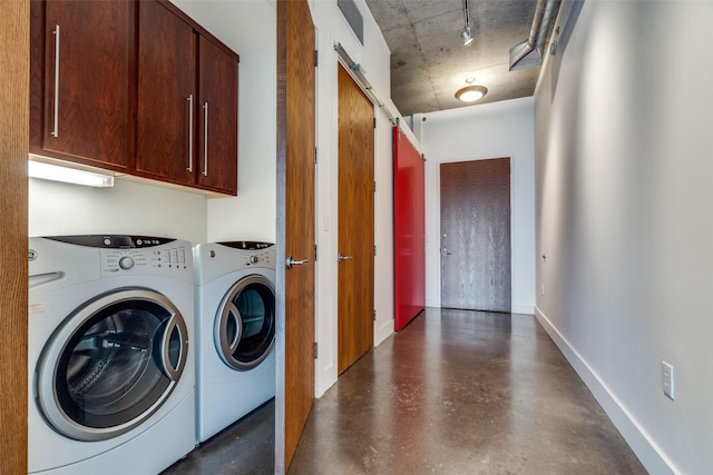 clothes washing area with washing machine and dryer, cabinet space, baseboards, and a barn door