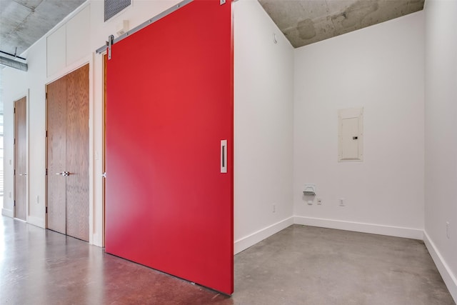 interior space with visible vents, a barn door, concrete flooring, electric panel, and baseboards