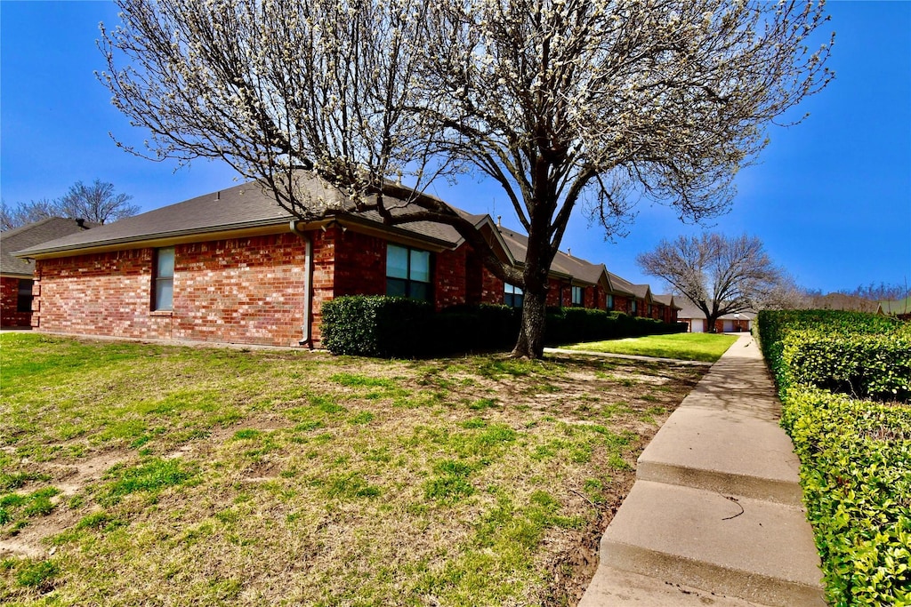 view of property exterior with brick siding and a lawn