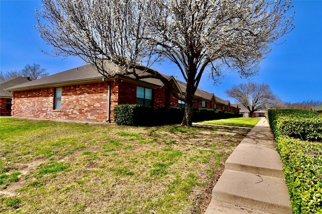 view of property exterior with brick siding and a lawn