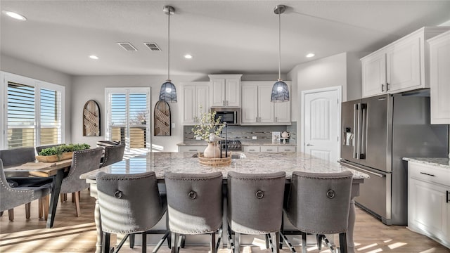 kitchen featuring stainless steel appliances, a center island, white cabinetry, and light wood-style floors