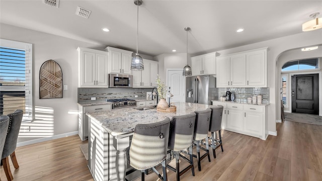 kitchen featuring visible vents, light wood-style flooring, white cabinetry, a sink, and high quality appliances