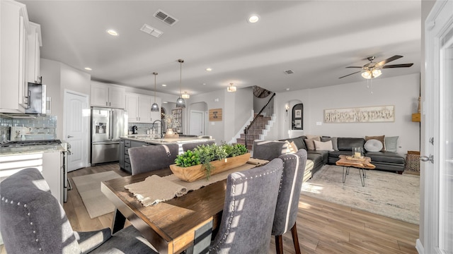 dining room featuring arched walkways, recessed lighting, visible vents, stairway, and light wood-style floors